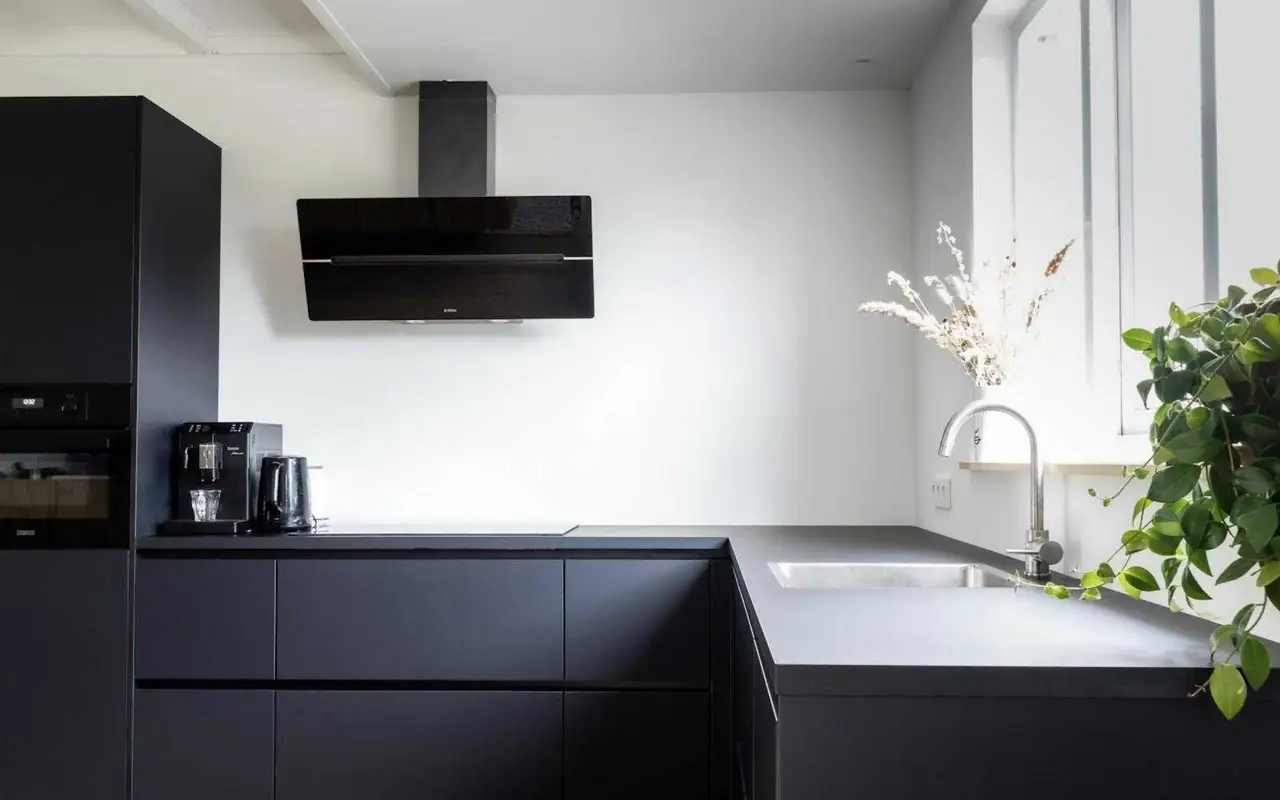 Cucina moderna con ante nere opache e pavimento in legno
